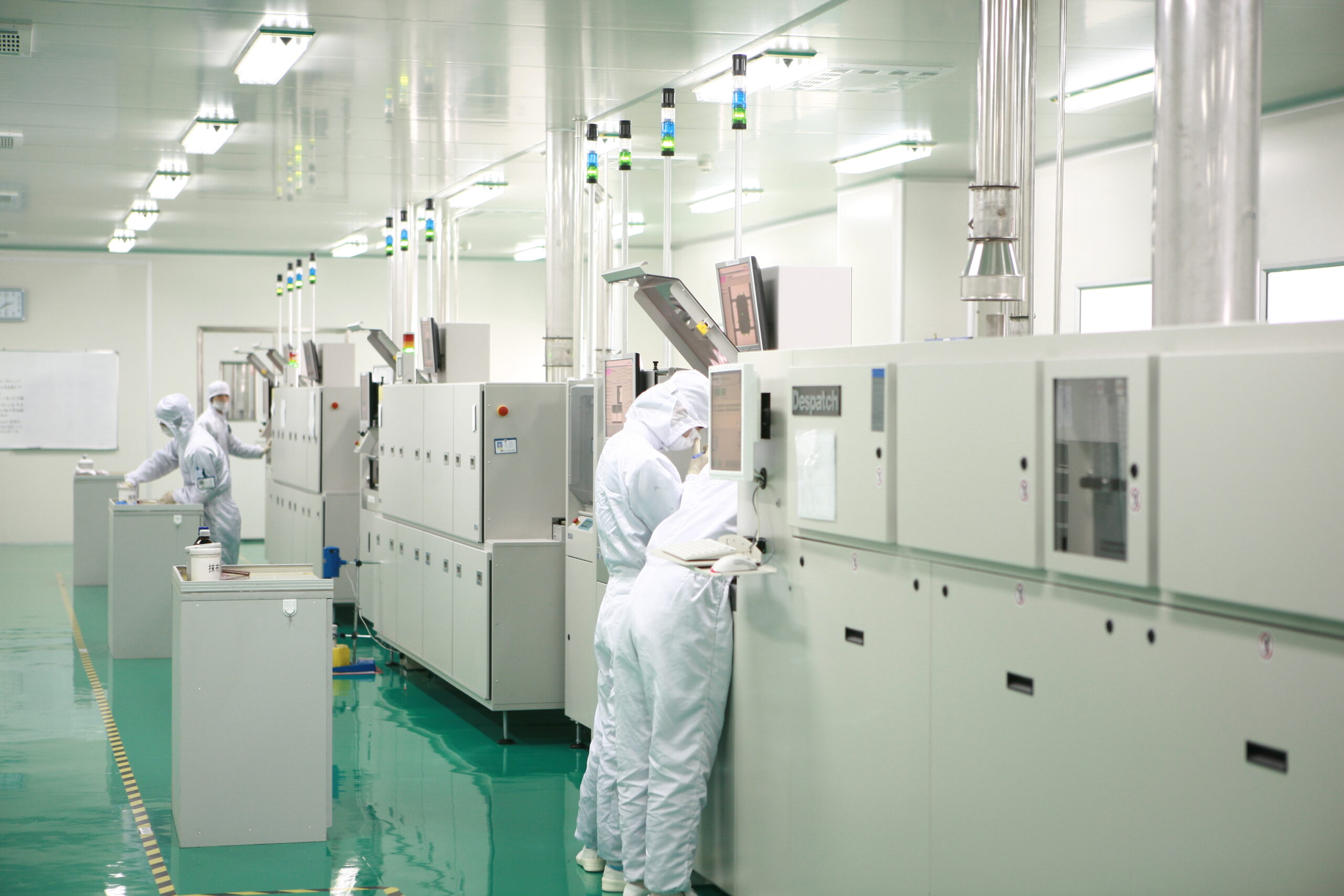 Workers in a cleanroom operating manufacturing equipment, advanced production environment